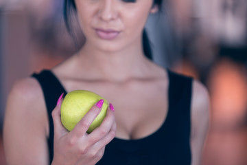 Torso of a woman with a green apple on a dark background