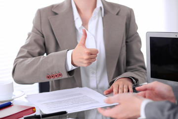 Group of business people or lawyers at meeting  discussing contract papers. Woman showing thumb up