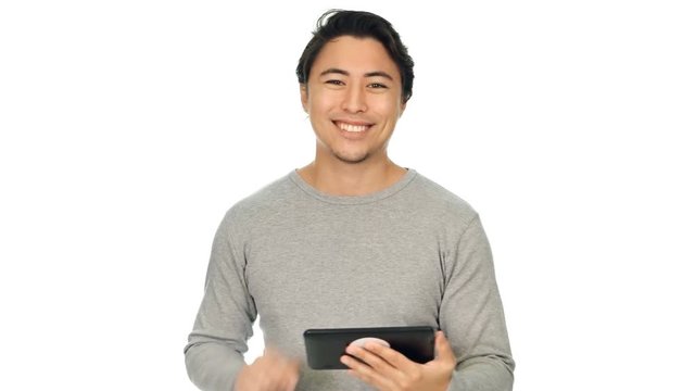 A calm man wearing a grey shirt against a white background, holding a digital tablet and swiping.