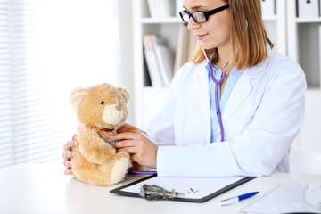 Obraz na płótnie Canvas Female doctor examining a .Teddy bear patient by stethoscope. Children medical care concept
