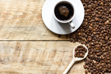 cup of coffee, beans and spoon on wooden background
