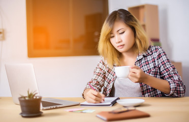 business woman writing something on notepad in office.