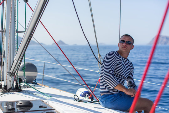 Young man sits on yacht. Luxury sailing boats. Travel, vacation.