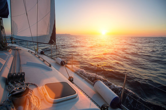 Amazing sunset at sea shot of a luxery yacht boat. Sailing in the wind through the waves.