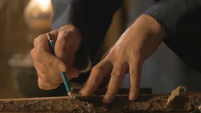 master carpenter makes basting on the Board with a pencil, draws, craftsman work tool in the workshop.