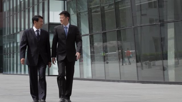 WS CU TU DEFOCUS Two businessmen walking towards camera away from office building / Beijing, China