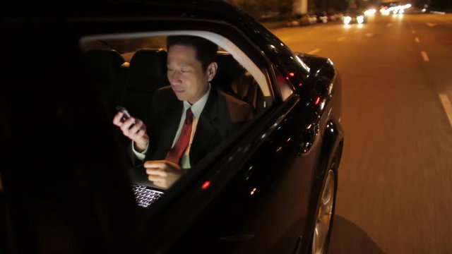 MH TS POV Businessman Riding in Back Seat of Car Talking on Phone at Night / Singapore