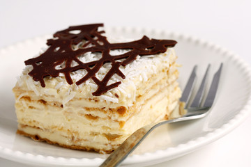 isolated slice of decorated with chocolate napoleon cake, served on white plate
