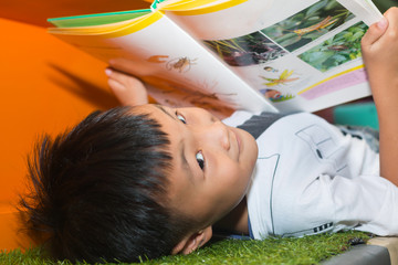 Cute little boy reading book in the library

