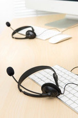 Microphone headsets on the table with computer keyboards in call center
