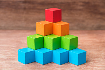 stack of colorful wood cube building blocks on wood background