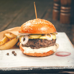 Beef burger with fries on a white wooden board