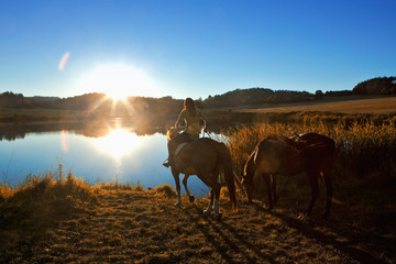 Woman with Two Horses by a Lake at Sunset