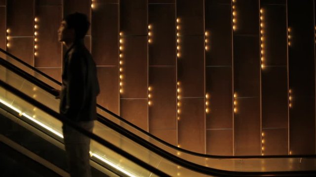 MS Young man going down on escalator at night / China