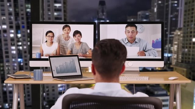Businessman in office at night talking to international co workers. Hispanic and Asian group of ethnically diverse group of business professional using video chat conference on computer