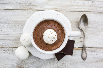 Delicious hot dark chocolate with marshmallows in a cup on a wooden table. Top view.