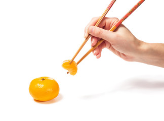 Female hand holding a slice of mandarin Chineses chopsticks. Isolated on white background.