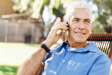 LoMature man outdoors using mobile phone