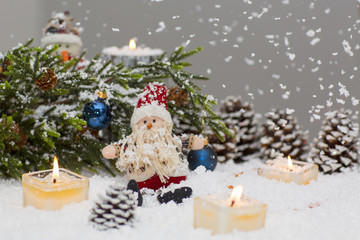Christmas still life is with snow. Toy Santa Claus is sitting under a Christmas tree.  