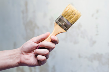 Hand with a brush  on a background of ragged wall