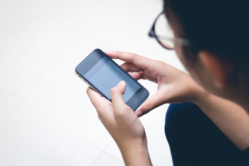 Woman with modern mobile phone in hands touching on a blank scre