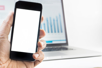 Hand holding Blank Screen of Smart phone with blurred graph on laptop