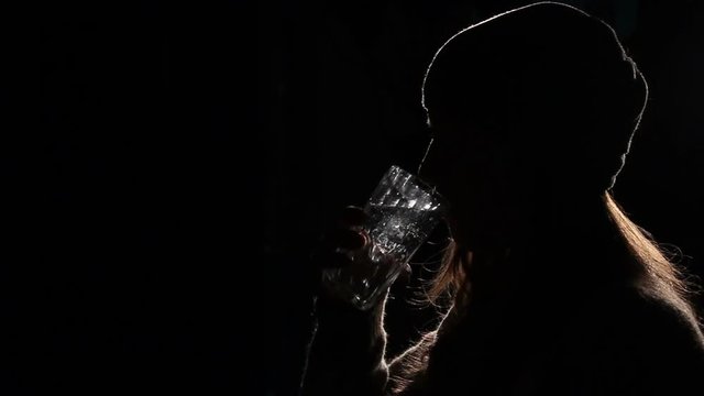 Silhouette Of A Woman. Drinks With Fresh Water From A Glass