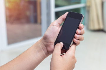 Woman with modern mobile phone in hands touching on a blank scre