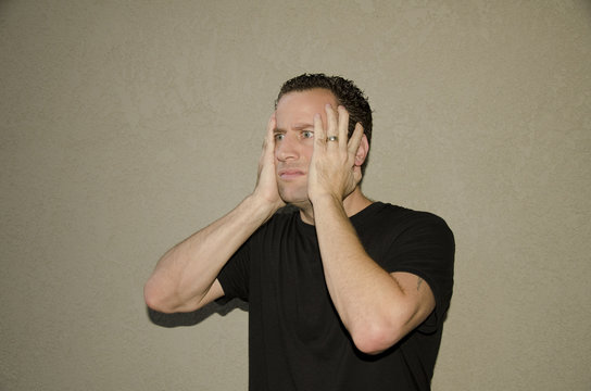 Shocked man alone with hands on his face