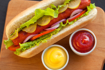 Barbecue Grilled Hot Dog with Yellow Mustard and ketchup on wooden table
