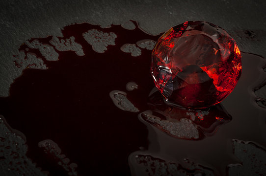 Blood diamond concept with a diamond covered in red blood in a dark setting resembling a mine with copy space