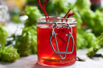 Close-up of cherry jelly in glass jar, green background of hop. Sweet red yummy jam with fresh cherries in it. Dessert, confectionery concept