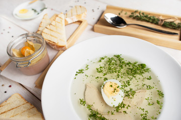Hot bouillon with toasts and pate top view. Served plate of broth with egg and crusty bread with foie gras. French cuisine, restaurant menu, luxury food ,healthy dinner concept