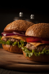 Home made hamburger with beef, onion, tomato, lettuce and cheese. Fresh burger closeup on wooden rustic table with potato fries, beer and chips.