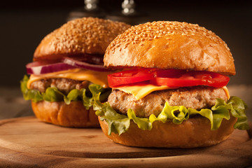 Home made hamburger with beef, onion, tomato, lettuce and cheese. Fresh burger closeup on wooden rustic table with potato fries, beer and chips.