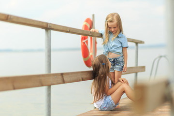 two child girls playing on a pier on the beach or riverbank