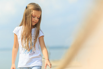 Fototapeta na wymiar Child girl stain on a pier on the beach or riverbank