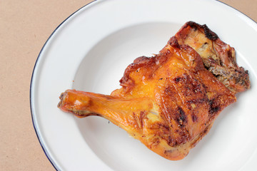 Grilled chicken leg in white dish on wooden background