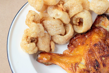 Streaky pork with crispy crackling and Grilled chicken leg in white dish on wood table. close-up. horizontal view from above. Thai Food