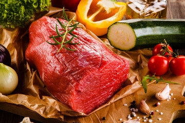 Fresh raw beef on cutting board and vegetables