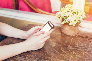 close up hand woman using phone in coffee shop with vintage tone
