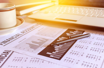 close-up pen with company's analysis report on investor's desk. Analysis business concept. over sunlight and use a soft focus. warm tone 

