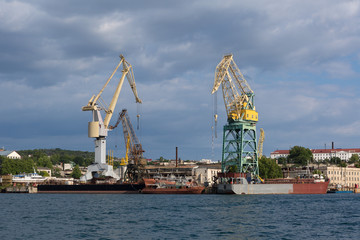 Fototapeta na wymiar Lifting cargo cranes at the shipyard in Bay of Black Sea.