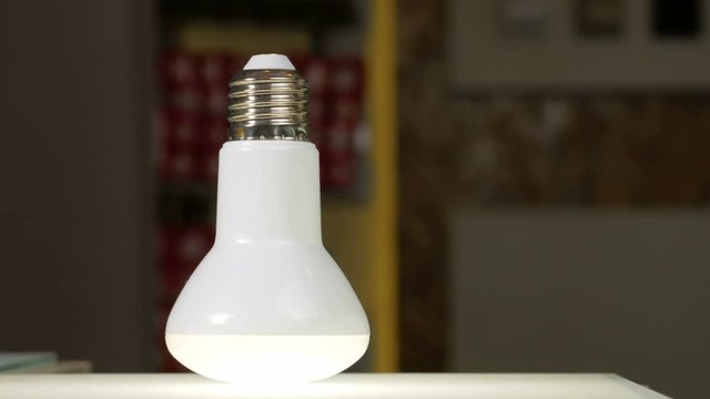 LED light bulb is glowing on the bench in the shop. Moving the camera. Close-up