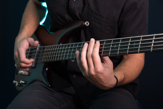 Young man playing electric guitar on dark background