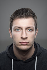 Obraz premium Close up moody vertical portrait of young casual man wearing sports hoodie looking at camera