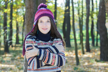 Freezing young woman wearing knitted woolly hat and embracing herself