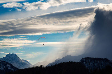 Mountain paragliding between wind and clouds