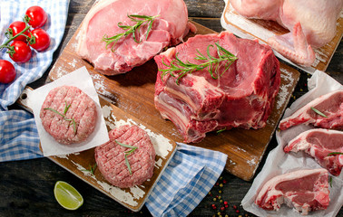 Different types of raw meat with fresh vegetables and herbs on a
