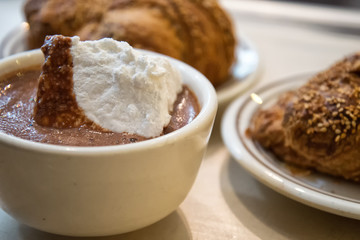 Hot chocolate with marshmallow and croissants in the background